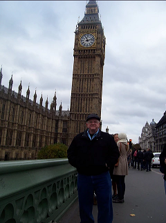 Terry wears a jacket and newsboy cap as he poses for a photo with Big Ben clock tower in the near distance.