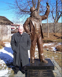 Terry poses in an overcoat next to a bronze statue of Walt Whitman.
